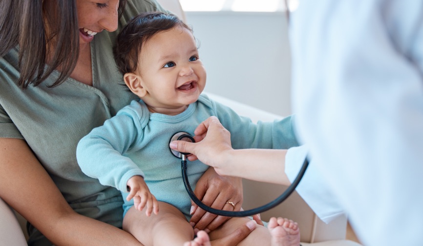 Baby in blue top, getting heart checked by doctor using stethoscope