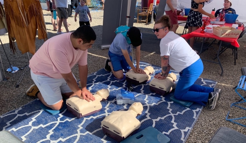 Teen and adults practising CPR training on Brayden Manikins, outdoors